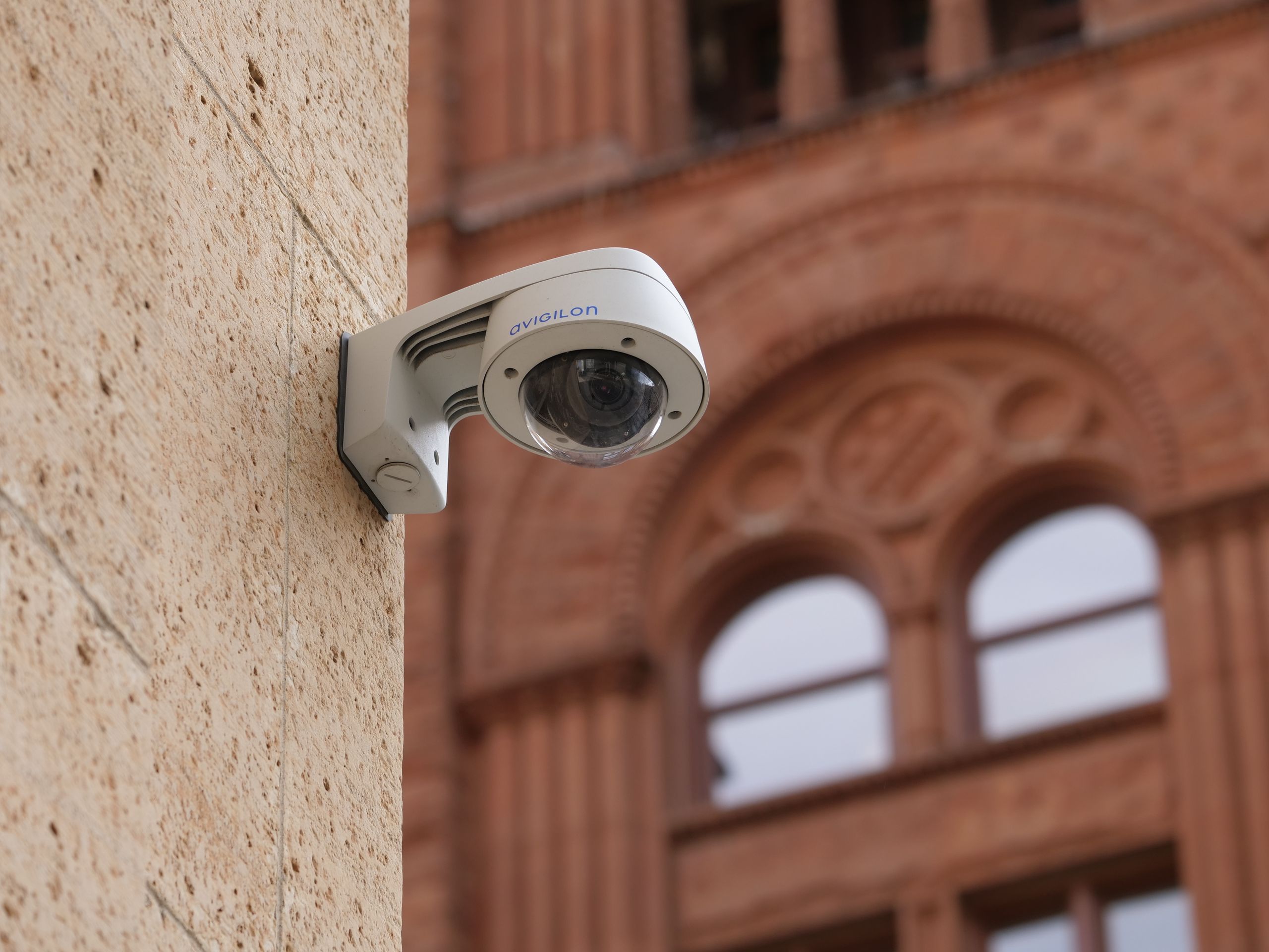 Wall-mounted dome security camera on a city building, enhancing public safety.